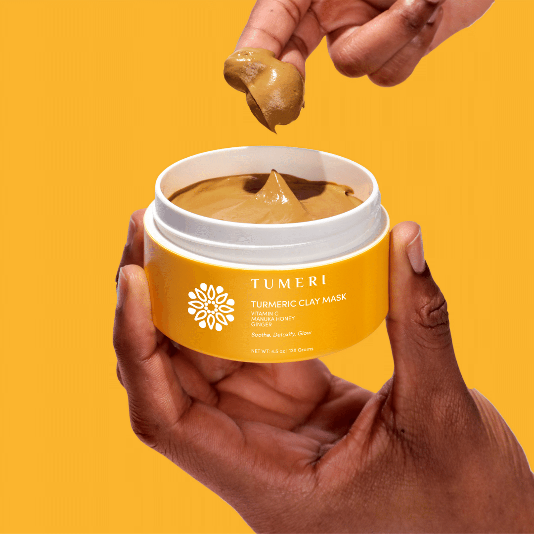 Hand applying tumeric clay mask